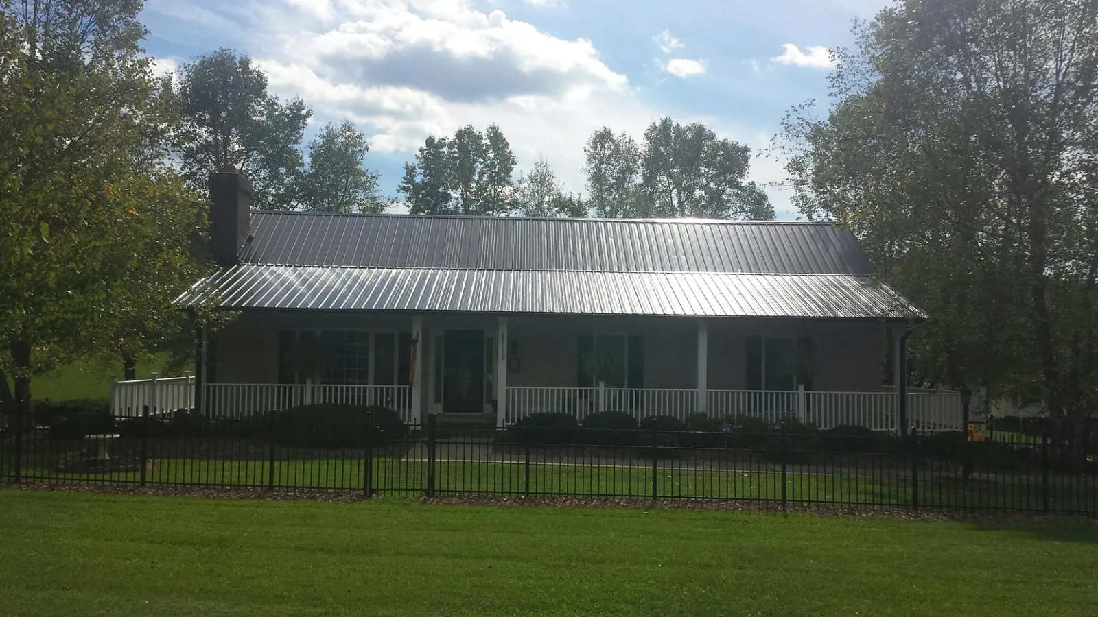 Gray metal roof on a brick ranch with a full width front porch — Gutter Guard Installation work by our crew in Concord
